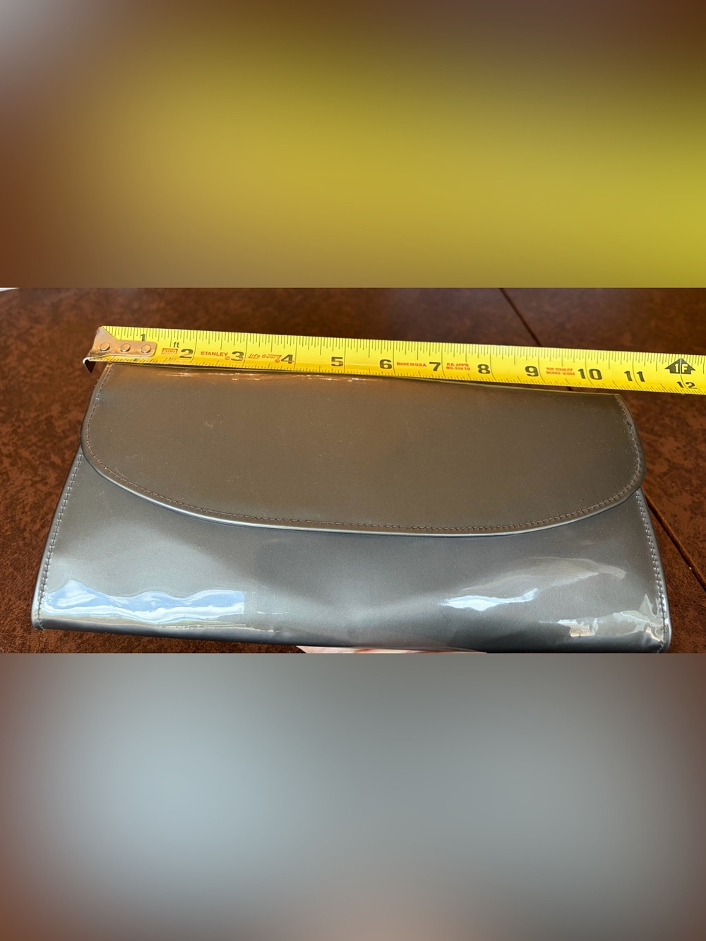 Glossy, grey patent leather clutch with wrist strap